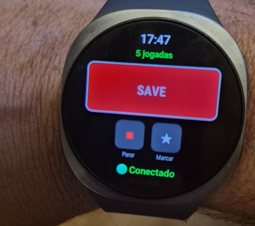 Relógio Wear OS no pulso mostrando o botão SAVE, os botões Parar e Marcar, o contador de jogadas da sessão e o status Conectado